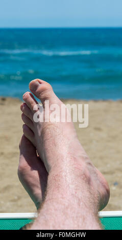Un mans piedi appoggiati sul bordo di un lettino su una spiaggia del sud della Spagna Foto Stock