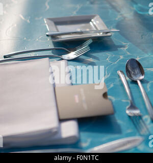 Vestito vuoto tavolo blu con forchette, coltelli, cucchiai e tovaglioli in un ristorante Foto Stock