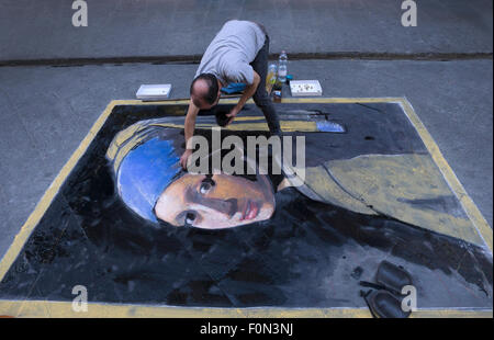 Uomo al lavoro su street chalk disegno di Vermeer donna con perla earing. Foto Stock