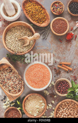 Assortimento di legumi di granella e semi. Vari tipi di cereali, riso e legumi spezie ed erbe in ciotole sul tavolo rustico Foto Stock