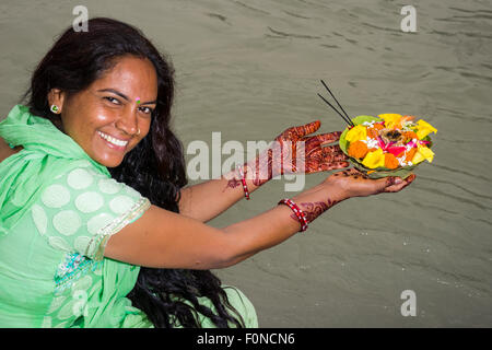 Una giovane donna con lunghi capelli neri, Henna dipinto di mani e un abito verde è in possesso di un Deepak, un fiore che offre, al ghats Foto Stock