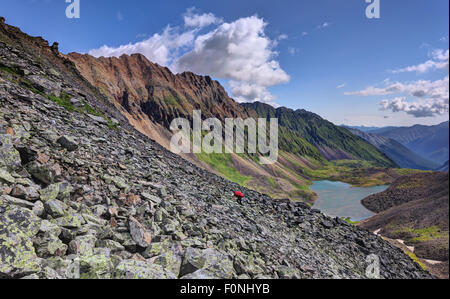 Turismo in montagna. La morena laterale e la donna escursionista salendo a piedi lungo la morena. Eastern Sayan. Buryatia Foto Stock