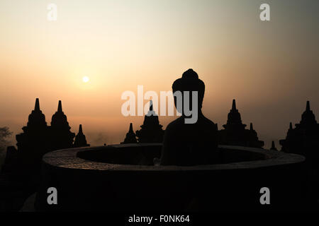 Sagome di una statua del Buddha presso il sito patrimonio mondiale dell'Unesco il tempio di Borobudur all'alba sull isola di Giava, in Indonesia, in Asia. Foto Stock