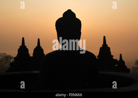 Sagome di una statua del Buddha presso il sito patrimonio mondiale dell'Unesco il tempio di Borobudur all'alba sull isola di Giava, in Indonesia, in Asia. Foto Stock