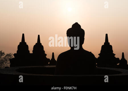 Sagome di una statua del Buddha presso il sito patrimonio mondiale dell'Unesco il tempio di Borobudur all'alba sull isola di Giava, in Indonesia, in Asia. Foto Stock