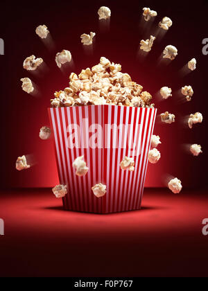 Colpo di stile cinema popcorn in un tradizionale cassetta con pezzi di volare è una commedia di moda. La sfocatura sui pezzi viene creato Foto Stock