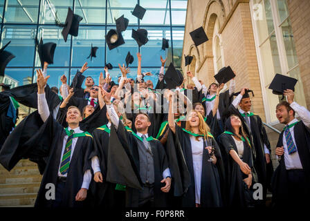 I nuovi diplomati celebrando gettando malta le schede in aria il giorno di graduazione Foto Stock