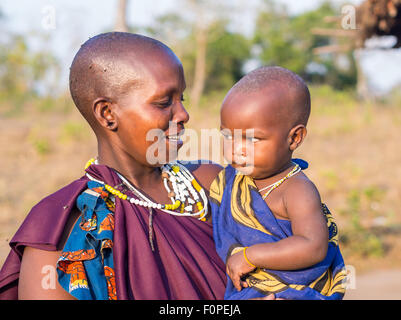 Maasai madre tenendo in braccio il bambino nella loro boma (paese) in Tanzania, Africa. Foto Stock