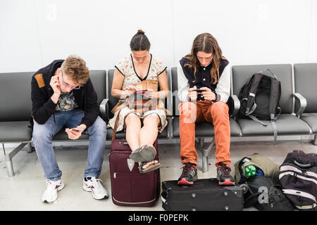 Passeggeri,i viaggiatori, con, trasportare su,mano, bagagli, controllo, loro, mobile, dispositivi al terminal partenze, at, Stansted Airport,Londra,U.K. Foto Stock