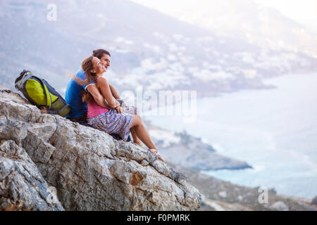 Coppia giovane seduto sulla roccia e gode di splendida vista. Kalymnos Island, Grecia. Foto Stock