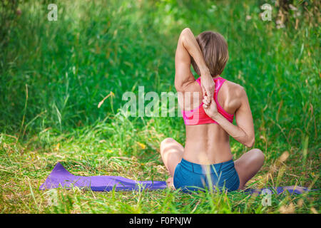 Giovane donna caucasica seduto e stirando le braccia dietro la schiena Foto Stock