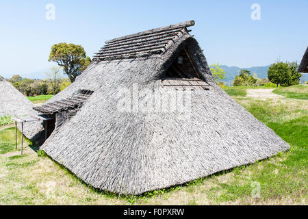 Giappone, Yoshinogari iron age Historical Park. Minami-no-mura, Sud Villaggio, ricostruito periodo Yayoi ferro-età pit-dimore.sotto il cielo blu chiaro. Foto Stock