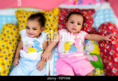 Ritratto di twin baby fratelli felicemente condividendo un letto insieme e giocare e sorridente con spazio di copia Foto Stock