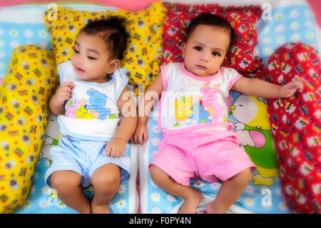 Ritratto di twin baby fratelli felicemente condividendo un letto insieme e giocare e sorridente con spazio di copia Foto Stock