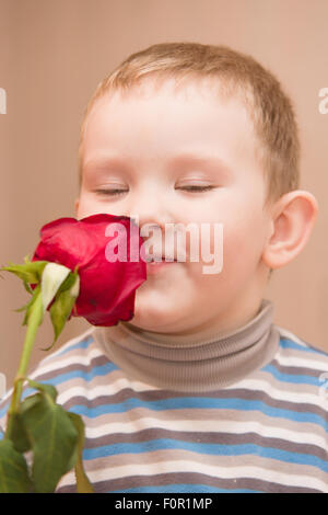 Il ragazzino con una rosa scarlatta in pensieri di cui al presente esso Foto Stock