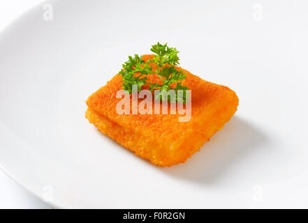 Pezzo di pesce fritto con prezzemolo fresco sulla piastra bianca Foto Stock