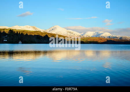 Snowy Coniston fells (Dow Crag, Coniston Old Man e Wetherlam) riflesso in Coniston Water, Lake District, mattina Foto Stock