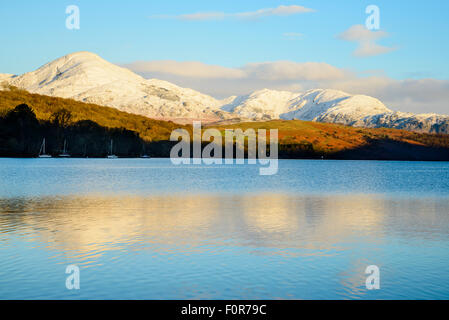 Snowy Coniston fells (Coniston Old Man e Wetherlam) riflesso in Coniston Water, Lake District, mattina Foto Stock