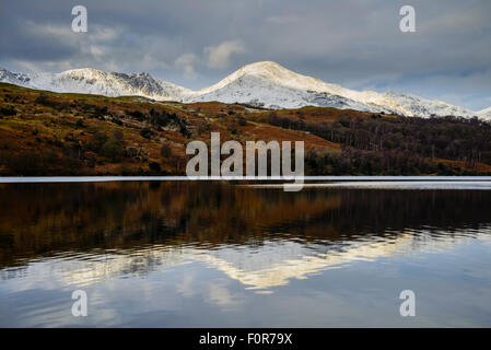 Snowy Coniston fells (Dow Crag e Coniston Old Man) riflesso in Coniston Water, Lake District Foto Stock