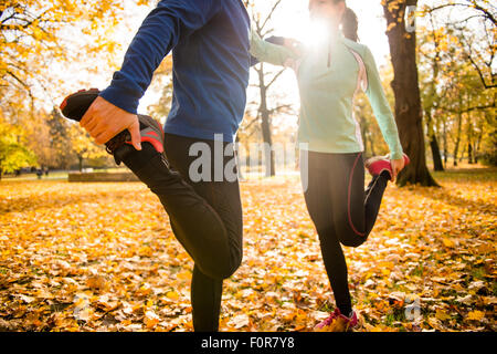 Dettaglio di un uomo e di una donna gambe stretching prima di fare jogging in autunno la natura Foto Stock