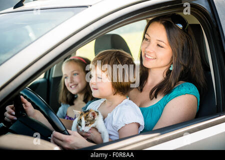 Madre e bambini fingere la guida auto tutti seduti sui sedili anteriori Foto Stock