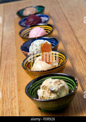 Una selezione di sei gelati con un brandy snap in piatti colorati. Foto Stock