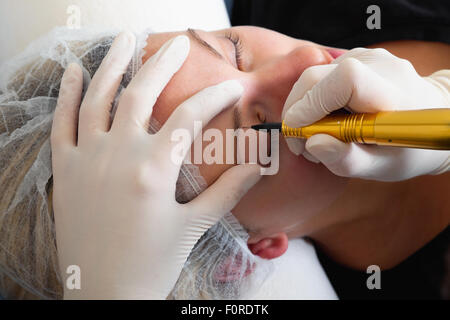 Cosmetologo rendendo trucco permanente sul volto di donna Foto Stock