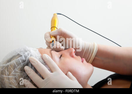 Cosmetologo rendendo trucco permanente sul volto di donna Foto Stock