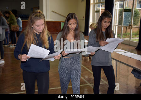 Tre ragazze adolescenti osservando attentamente la loro GCSE risultati esame nella sala principale della loro scuola. Foto Stock