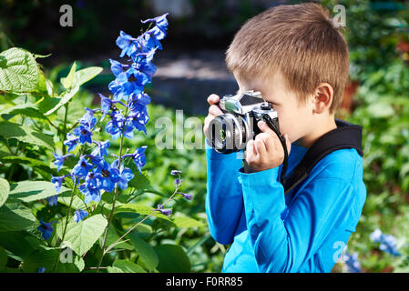 Ragazzino con retrò le riprese della telecamera di fiori blu Foto Stock