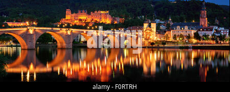 Panorama notturno di Ponte vecchio e storico castello di Heidelberg, Germania, che si riflette sull'acqua del fiume Neckar Foto Stock