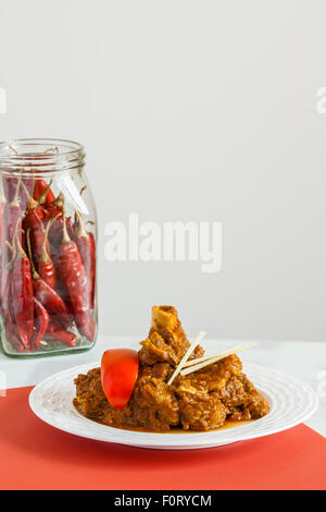 Indian montone rogan josh con guarnire (pomodoro, lo zenzero julienne) e il peperoncino rosso. Questo piccante piatto del Kashmir ha il peperoncino rosso. Foto Stock