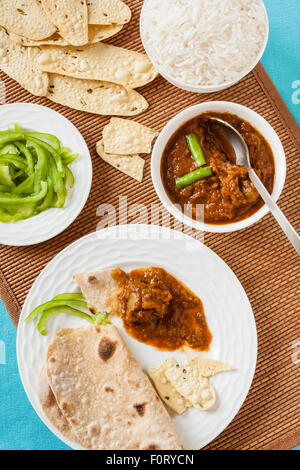 Degustazione di montone indiano rogan josh pasto con riso e chapati. Questo piccante piatto del Kashmir utilizza peperoncino rosso (pepe di cayenna). Foto Stock