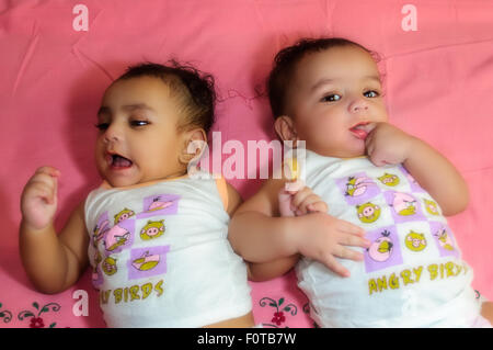 Ritratto di twin baby fratelli felicemente condividendo un letto insieme e giocare e sorridente con spazio di copia Foto Stock