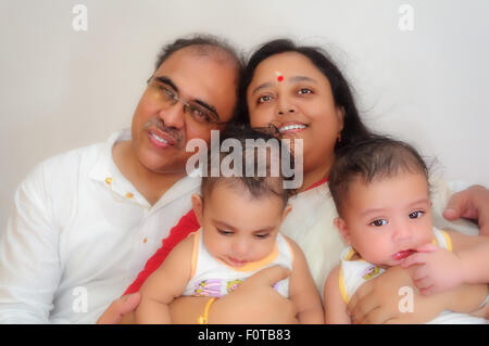 Ritratto di una famiglia felice dei genitori con twin baby boys che mostra legame, di amore, di affetto e di comunione con lo spazio di copia Foto Stock