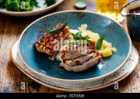 Pancetta di maiale con il crepitio, purè di patate e salsa di mele e fritte le foglie di salvia Foto Stock