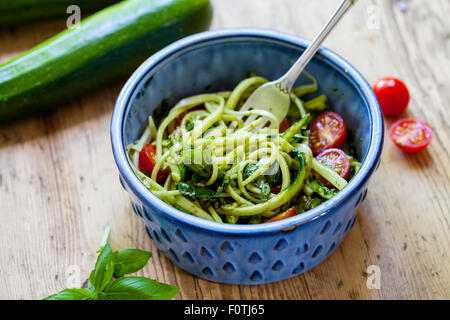 Gli spaghetti di zucchine con pomodorini e pesto di basilico Foto Stock