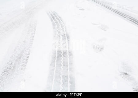 Primo piano delle tracce di pneumatici su una strada con la neve Foto Stock