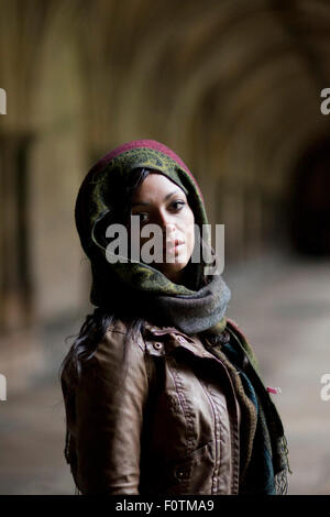 Basso-chiave di luce naturale Ritratto di giovane multi-etnico donna nei chiostri a Norwich Cathedral Foto Stock