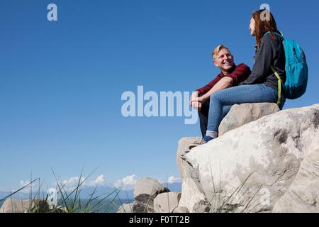 Basso angolo vista della coppia giovane seduto sulle rocce sorridente Foto Stock