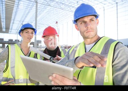 Surveyor e architetti con tavoletta digitale sul sito in costruzione Foto Stock