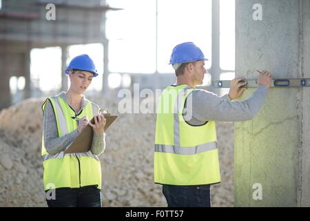 Builder utilizzando la livella a bolla sul sito in costruzione pilastro Foto Stock