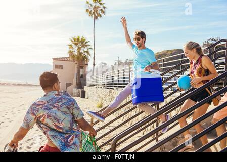 Gruppo di amici voce verso la spiaggia, pronto per picnic Foto Stock