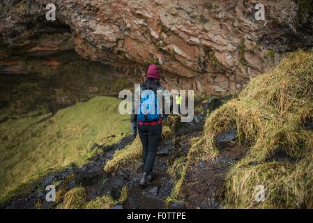 Due turisti percorrendo a piedi il percorso a cascata Seljalandsfoss, Islanda Foto Stock