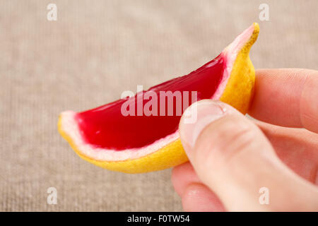 Maschio lato tenendo un limone tequila strawberry jelly (jella) shot. Messa a fuoco selettiva su un tiratore Foto Stock