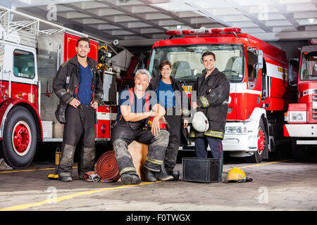 Felice vigile del fuoco della squadra con le apparecchiature presso la stazione dei vigili del fuoco Foto Stock