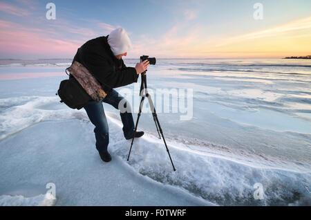 Fotografo di scattare foto sulla riva del fiume in inverno Foto Stock