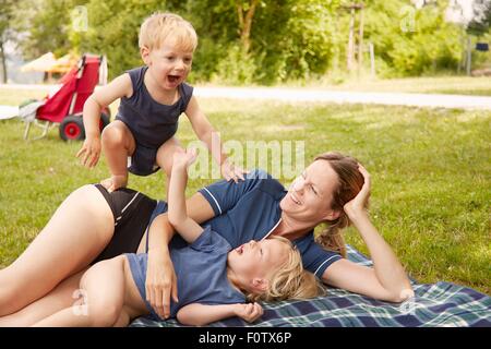 Madre e figli relax nel parco, giacente sulla coperta picnic Foto Stock