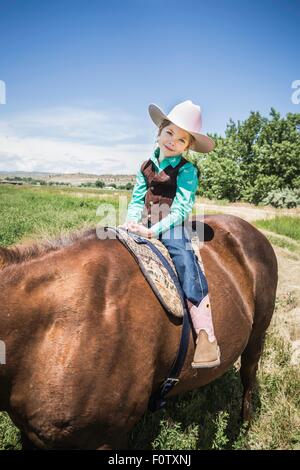 Ragazza indossare stivali da cowboy e hat a cavallo Foto Stock