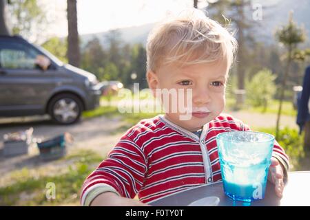 Ritratto di bimbi maschio di bere latte in foresta, Campeggio Lago di Dobbiaco, Dolomiti, Alto Adige, Italia Foto Stock